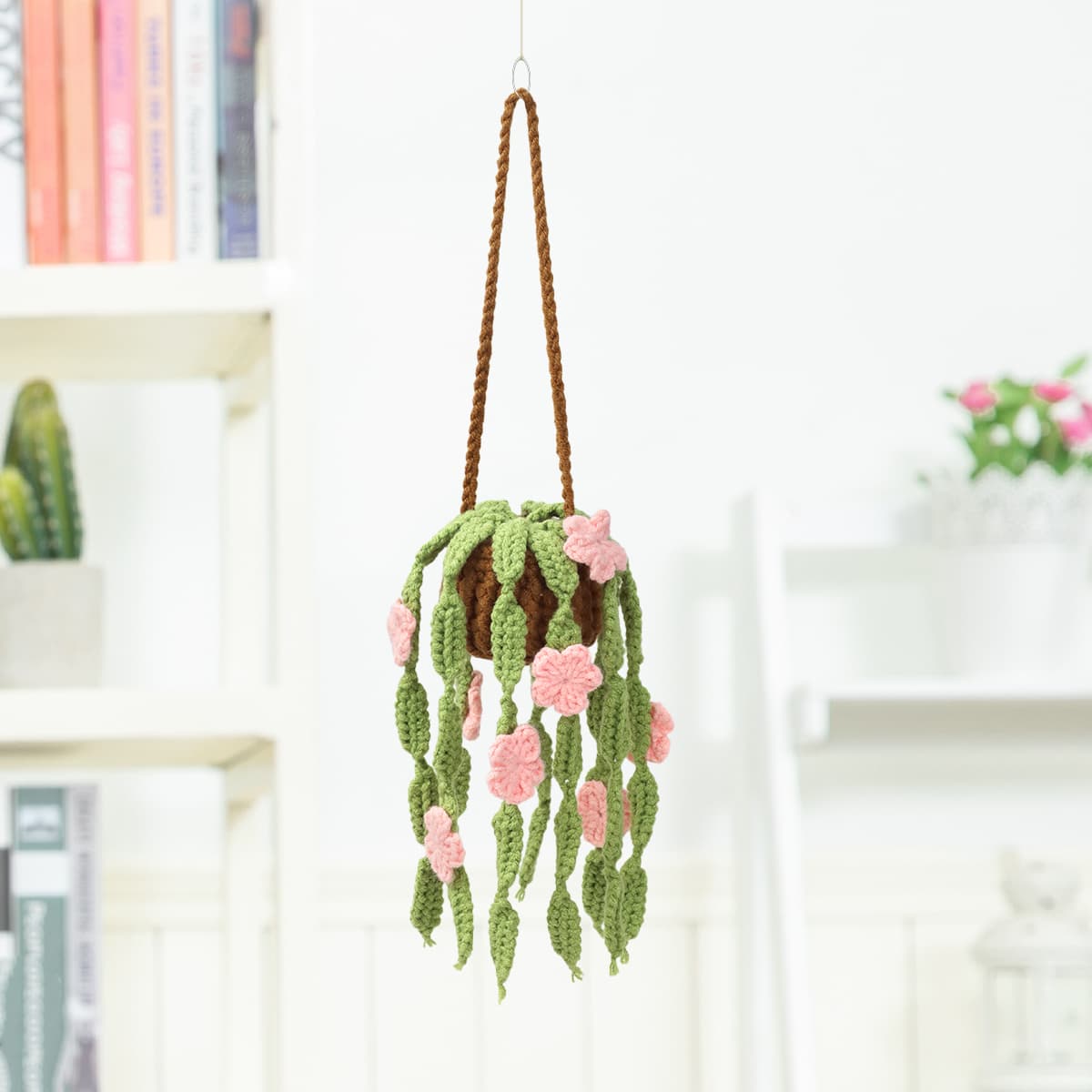 Planta colgante tejida al crochet con flores rosas y hojas verdes